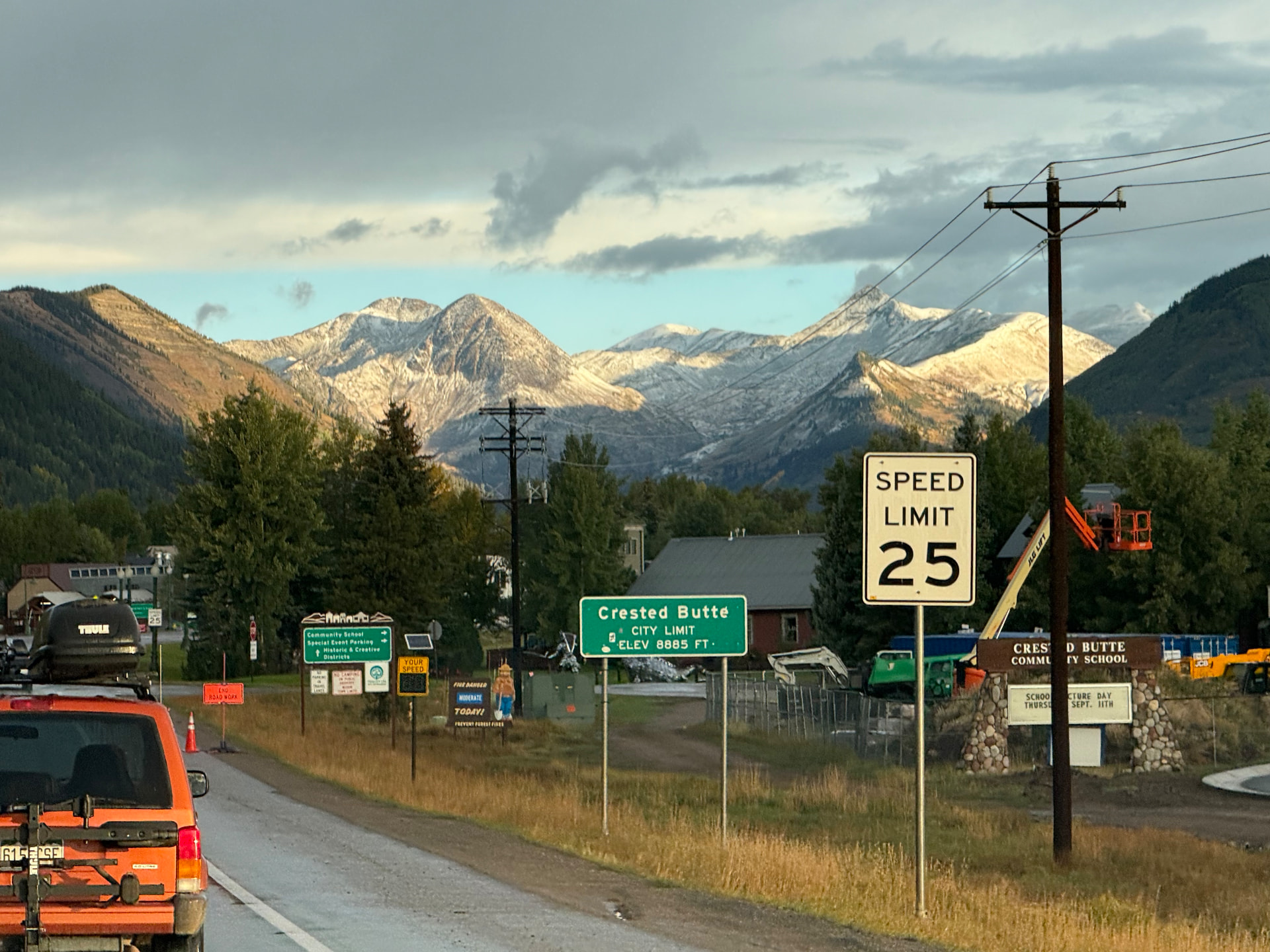 Crested Butte city limit sign beneath snow-capped mountains at the edge of town
